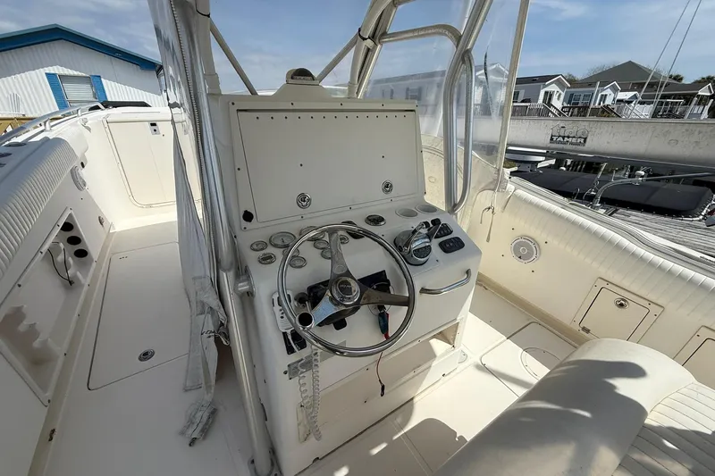 Slide: The Image of 2005 World Cat 330 TE boat helm with steering wheel and controls, docked near houses. - 21