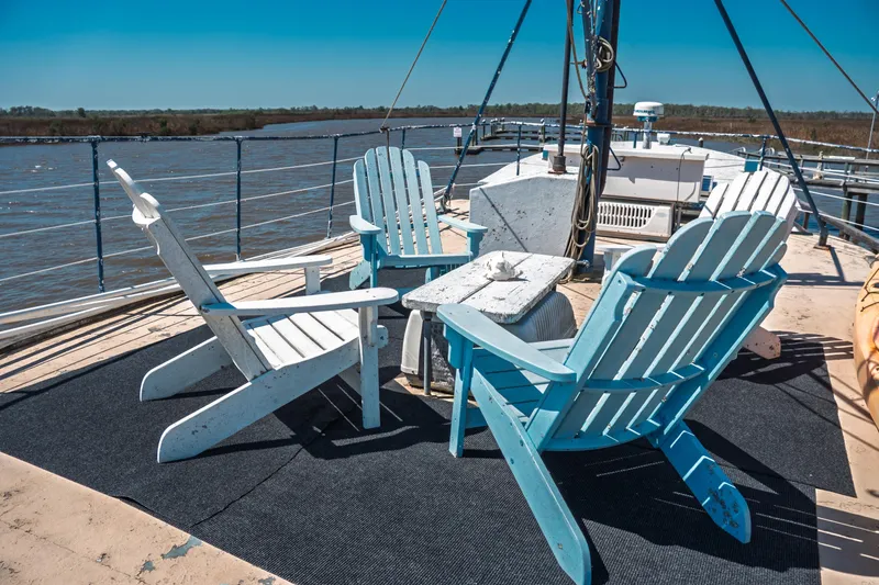 Slide: The Image of 1977 Saint Augustine Trawler deck with Adirondack chairs overlooking serene waters. - 13