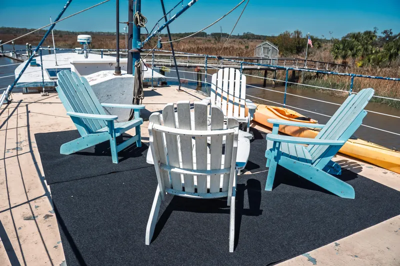 Slide: The Image of 1977 Saint Augustine Trawler 43 deck with Adirondack chairs and kayaks, docked by a scenic river. - 14