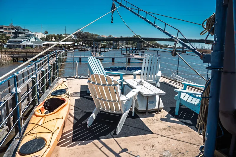Slide: The Image of Deck of 1977 Saint Augustine 43 Trawler with chairs and kayak, docked by waterfront. - 19