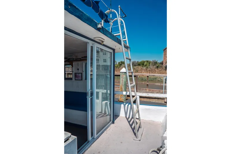 Slide: The Image of 1977 Saint Augustine 43 Trawler with ladder and sliding glass door, docked under clear blue sky. - 23