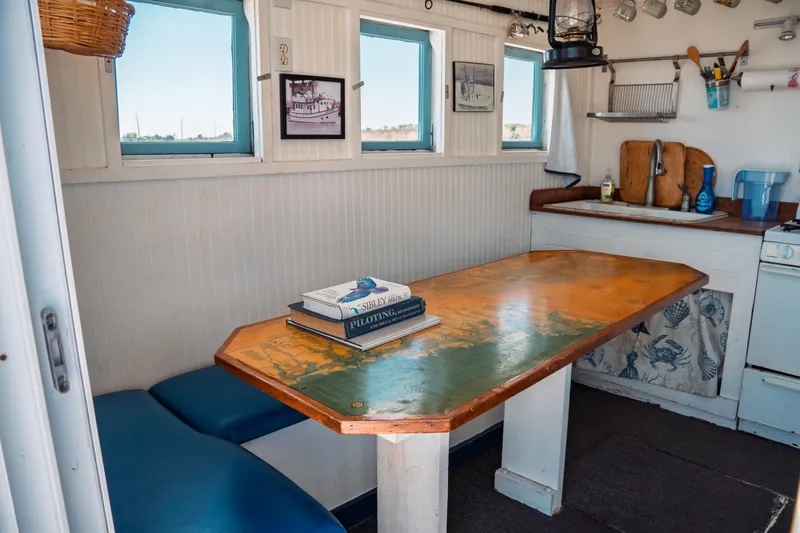 Slide: The Image of 1977 Saint Augustine Trawler 43 interior with wooden table, books, and kitchenette. - 26