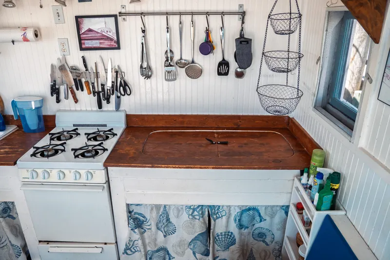 Slide: The Image of 1977 Saint Augustine Trawler 43 kitchen with stove, utensils, and hanging baskets. - 28