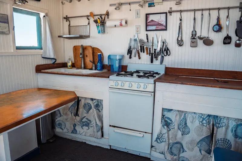 Slide: The Image of 1977 Saint Augustine Trawler 43 kitchen with stove, utensils, and nautical-themed decor. - 29