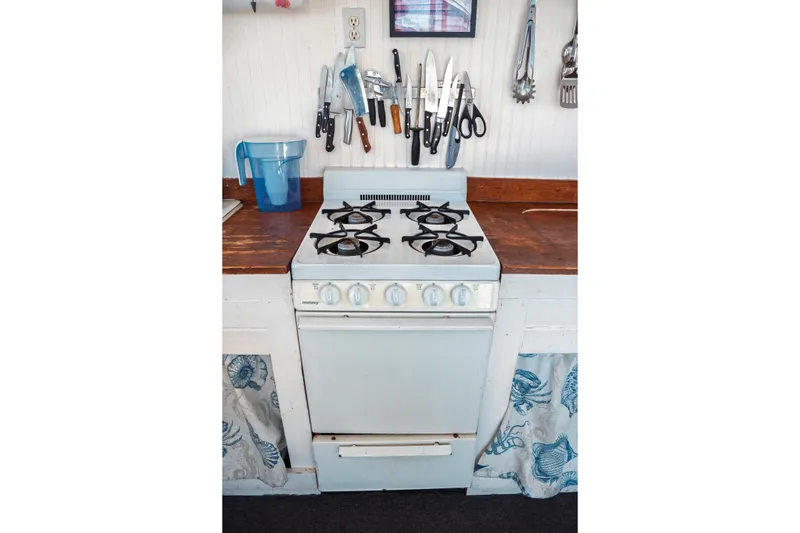 Slide: The Image of 1977 Saint Augustine Trawler kitchen with vintage stove, wooden countertop, and hanging utensils. - 31