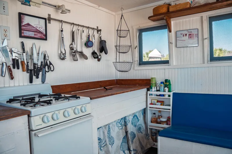 Slide: The Image of 1977 Saint Augustine Trawler 43 kitchen with stove, utensils, and blue seating. - 35