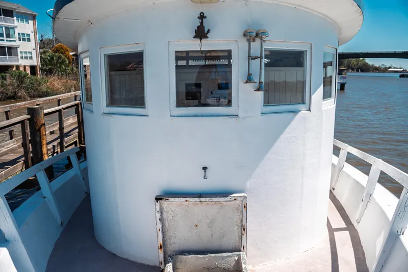 Slide: The Image of 1977 Saint Augustine 43 Trawler, white exterior, docked by a riverside with buildings and bridge. - 39