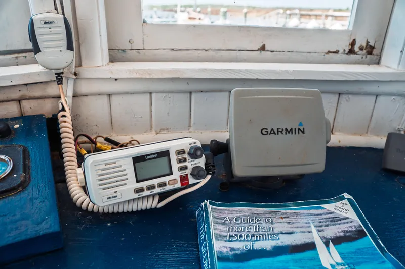 Slide: The Image of 1977 Saint Augustine Trawler 43 cockpit with Uniden radio, Garmin GPS, and nautical guidebook. - 44