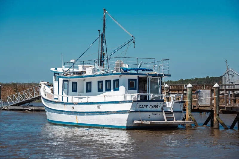 Slide: The Image of 1977 Saint Augustine 43 Trawler docked, named "Capt Gabby," under clear blue sky. - 5