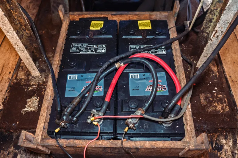 Slide: The Image of Battery setup in a 1977 Saint Augustine 43 Trawler, featuring cables and wooden frame. - 67