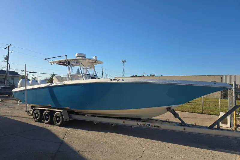 The Image of 2012 Fountain 38 CC Tournament Edition boat on trailer, blue hull, sunny day. - 1