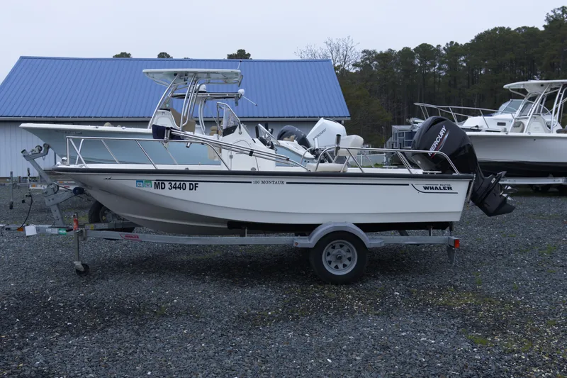 The Image of 2021 Boston Whaler 150 Montauk boat on trailer, parked outdoors. - 1