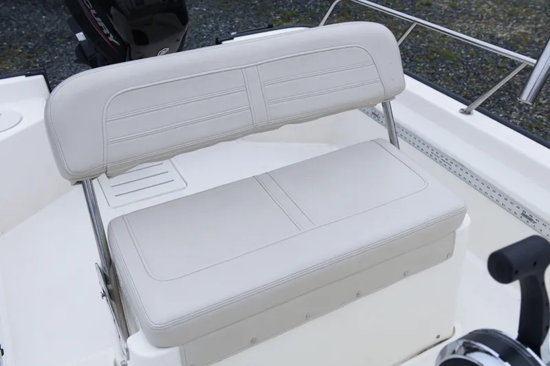 Slide: The Image of 2021 Boston Whaler 150 Montauk boat seat with white upholstery and stainless steel frame. - 12