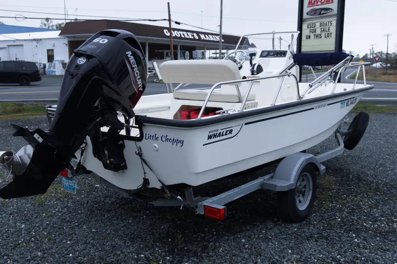 Slide: The Image of 2021 Boston Whaler 150 Montauk boat on trailer with Mercury engine, parked outdoors. - 5