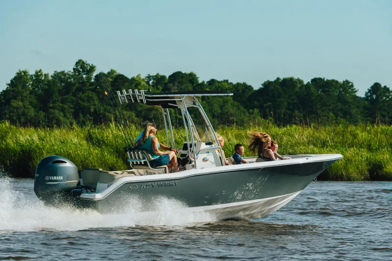 Slide: The Image of 2026 Key West 203 FS boat cruising on a river with passengers, lush greenery in background. - 10