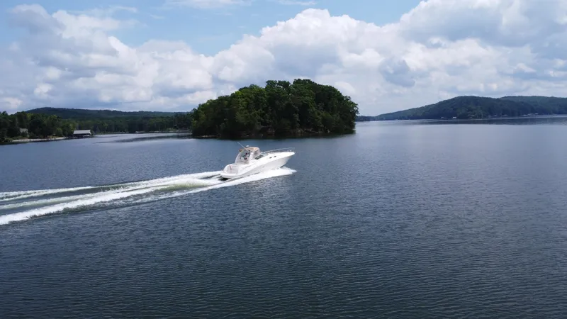Slide: The Image of 2003 Sea Ray 340 Sundancer cruising on a serene lake with an island in the background. - 11