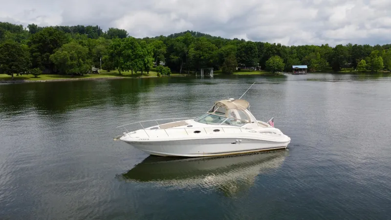Slide: The Image of 2003 Sea Ray 340 Sundancer boat on a serene lake with lush green trees. - 2