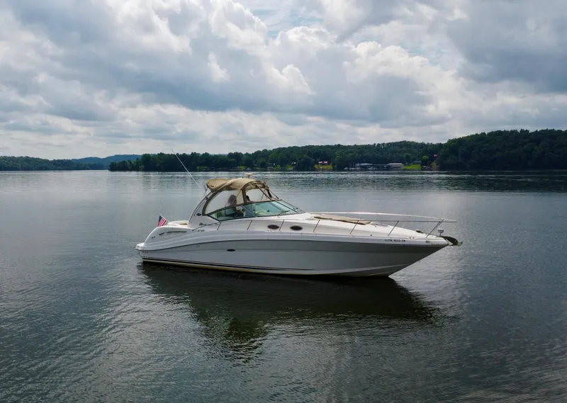 Slide: The Image of 2003 Sea Ray 340 Sundancer yacht on a calm lake under a cloudy sky. - 4