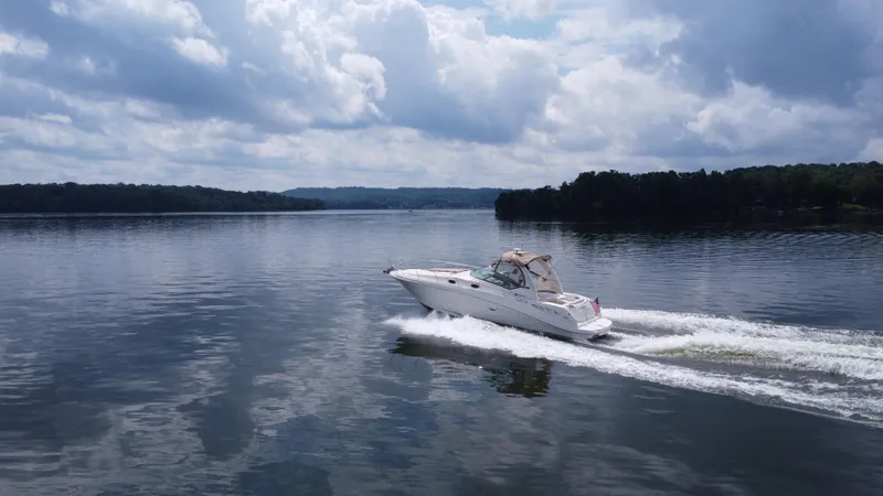 Slide: The Image of 2003 Sea Ray 340 Sundancer cruising on a lake under a cloudy sky. - 6