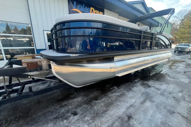 Slide: The Image of 2026 Harris Cruiser 230 CWDH pontoon boat on trailer outside dealership. - 6