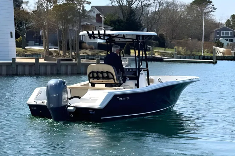 Slide: The Image of 2019 Tidewater 220 LXF boat cruising on a calm waterway near residential docks. - 10