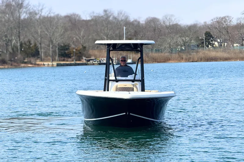 Slide: The Image of 2019 Tidewater 220 LXF boat cruising on a calm lake with wooded shoreline. - 12