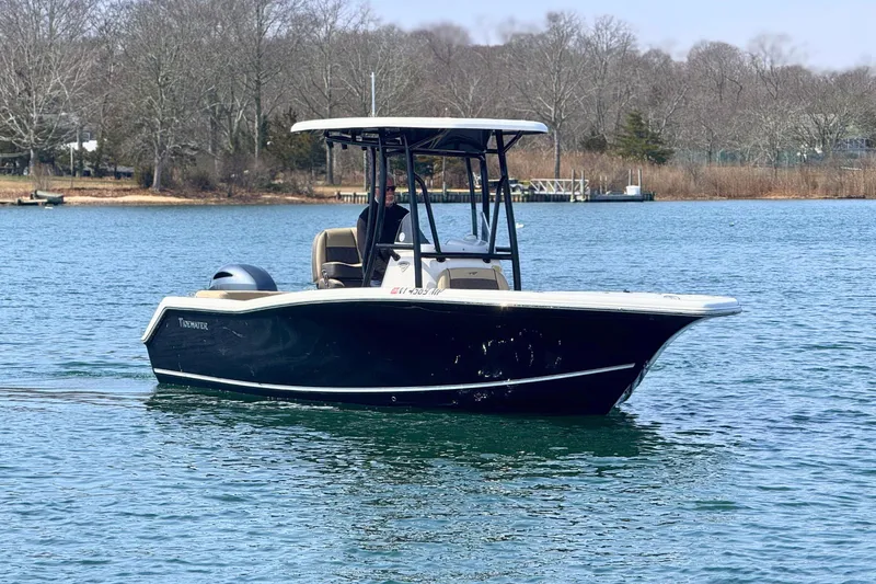 Slide: The Image of 2019 Tidewater 220 LXF boat cruising on a calm lake with wooded shoreline. - 4