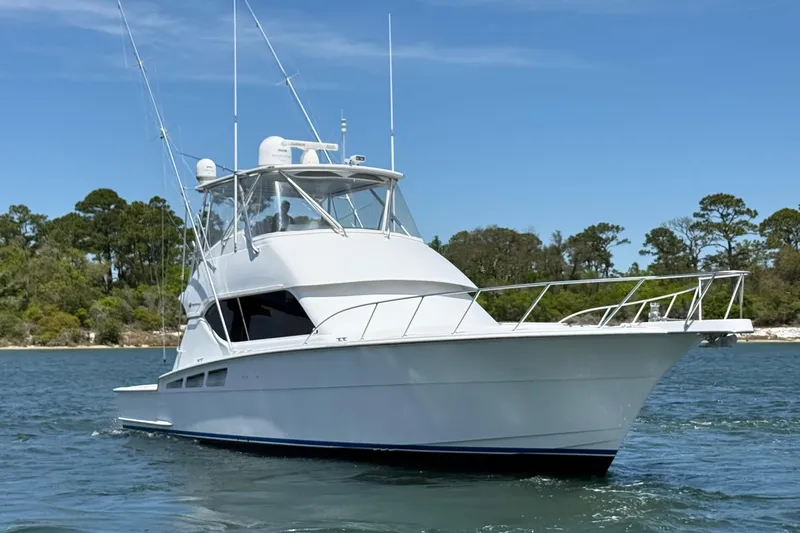 Slide: The Image of 2006 Hatteras 50 Convertible yacht cruising on a serene waterway with lush greenery. - 2