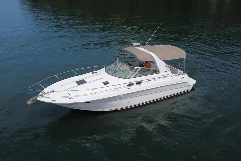 Slide: The Image of 2001 Sea Ray 310 Sundancer boat on calm water, featuring sleek design and beige canopy. - 1