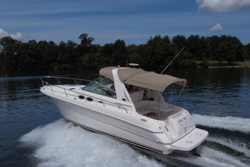 Slide: The Image of 2001 Sea Ray 310 Sundancer cruising on a serene lake with lush green shoreline. - 17