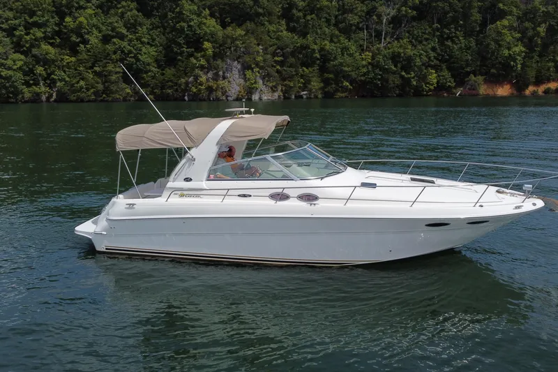 Slide: The Image of 2001 Sea Ray 310 Sundancer boat cruising on a serene lake with lush green forest backdrop. - 8
