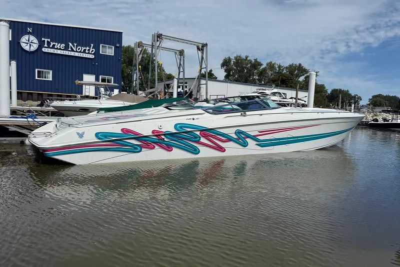 The Image of 1994 Formula 419 SR-1 boat with colorful graphics docked at marina. - 1