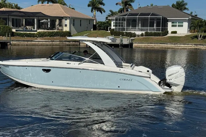 Slide: The Image of 2018 Cobalt 30SC boat cruising on a calm waterway near waterfront homes. - 10
