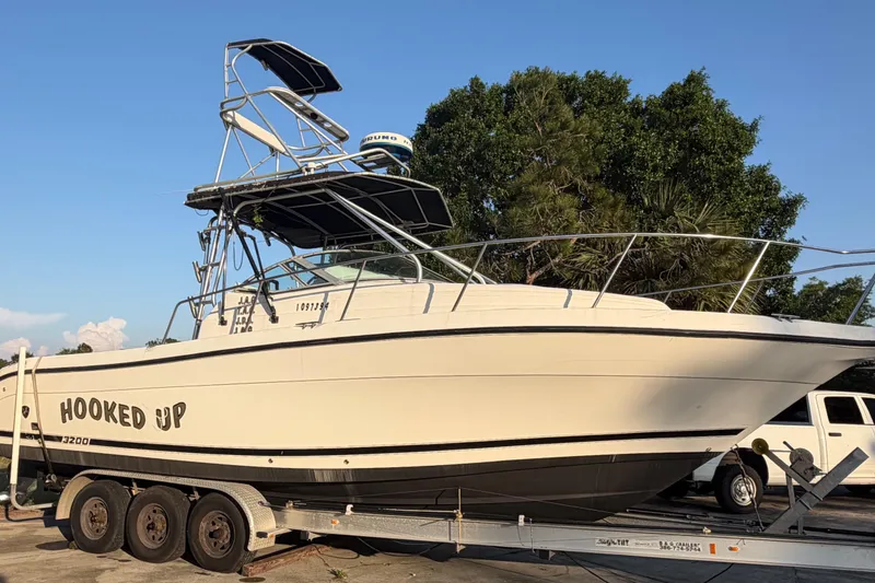 The Image of 2000 Century 3200 Walk-Around boat on trailer, labeled "Hooked Up," parked outdoors. - 1