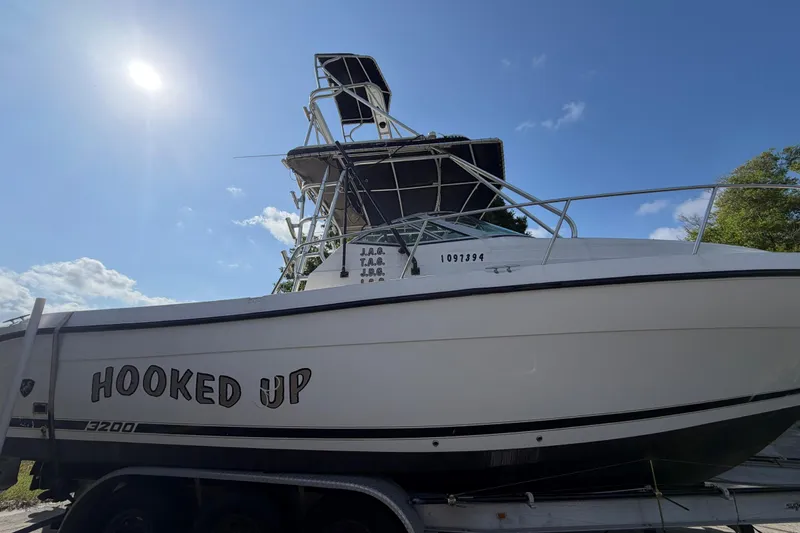 Slide: The Image of Century 3200 Walk-Around 2000 boat named "Hooked Up" on trailer under sunny sky. - 15