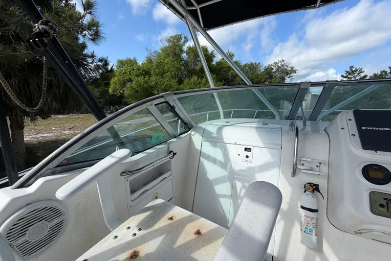 Slide: The Image of Century 3200 Walk-Around boat interior, featuring helm controls and seating, under a clear blue sky. - 44