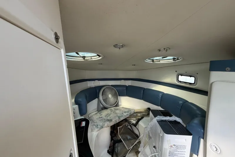Slide: The Image of Interior of a 2000 Century 3200 Walk-Around boat with blue seating and portholes. - 54
