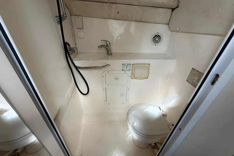 Slide: The Image of Compact bathroom in a 2000 Century 3200 Walk-Around boat, featuring a toilet and sink. - 63