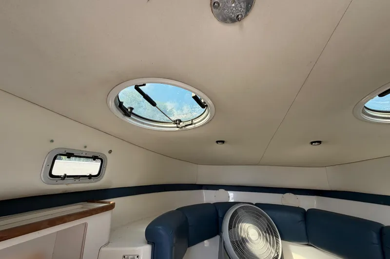 Slide: The Image of Interior of a 2000 Century 3200 Walk-Around boat with circular windows and seating. - 65
