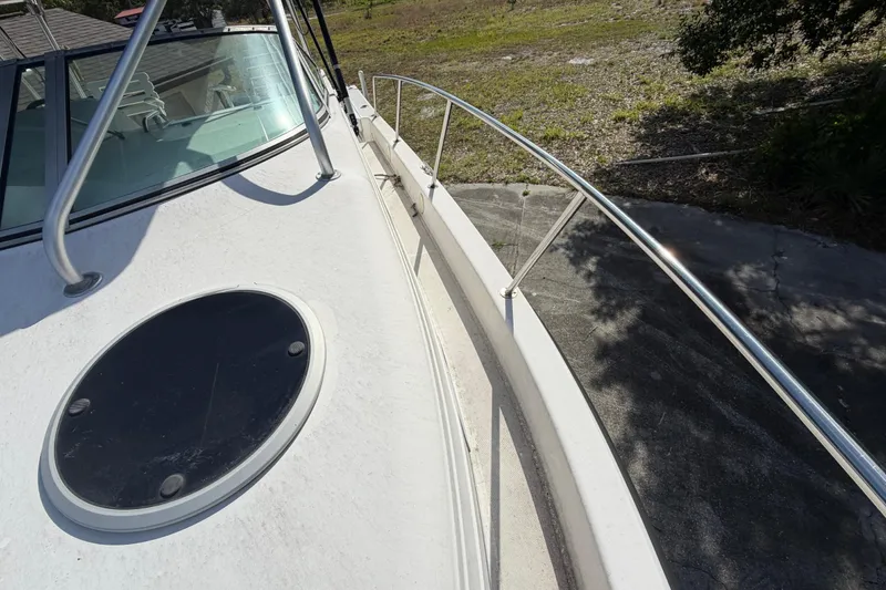 Slide: The Image of 2000 Century 3200 Walk-Around boat deck with railing and hatch, parked on land. - 74