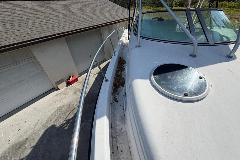 Slide: The Image of 2000 Century 3200 Walk-Around boat docked beside a garage, showing deck and railing. - 75