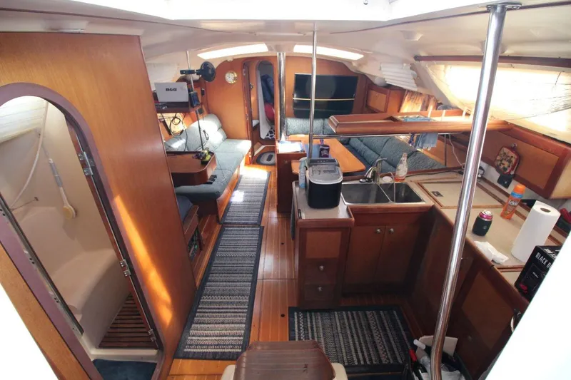 Slide: The Image of Interior of a 1999 Hunter 410 sailboat, featuring a cozy living area and kitchen. - 16