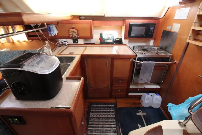 Slide: The Image of Compact kitchen area in a 1999 Hunter 410 sailboat with appliances and wooden cabinetry. - 19