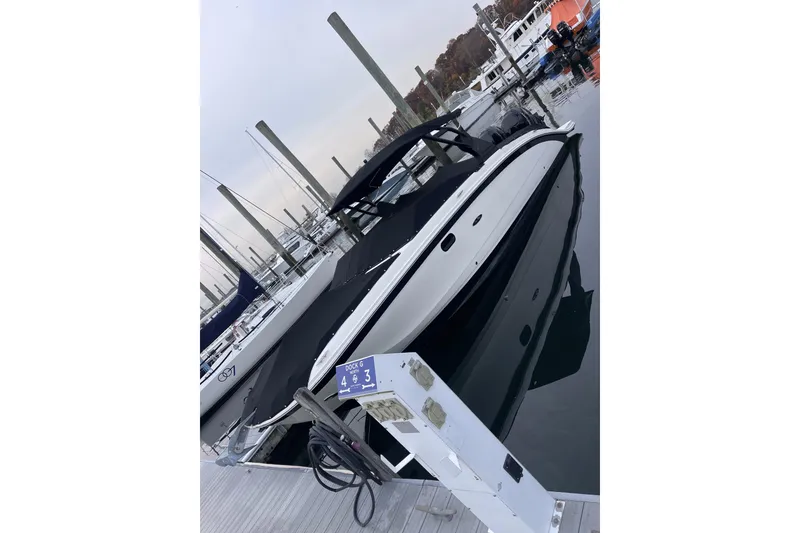 Slide: The Image of 2018 Sea Ray SDX 290 Outboard docked at marina, sleek design, black and white exterior. - 7