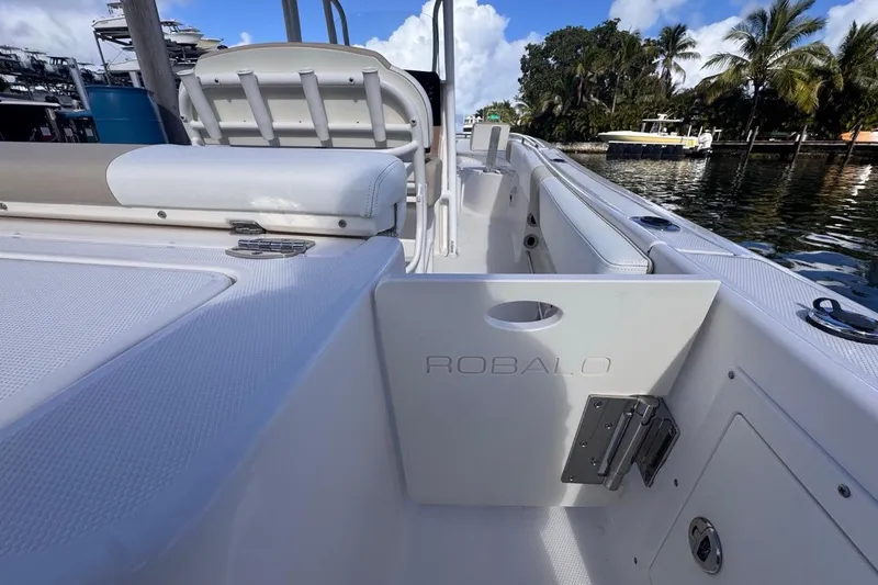 Slide: The Image of 2020 Robalo R242 Explorer boat interior with seating and storage, docked by palm trees. - 15