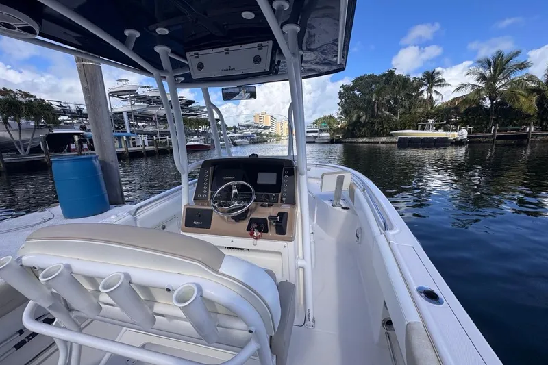 Slide: The Image of 2020 Robalo R242 Explorer boat interior with steering console, docked by a scenic waterfront. - 20