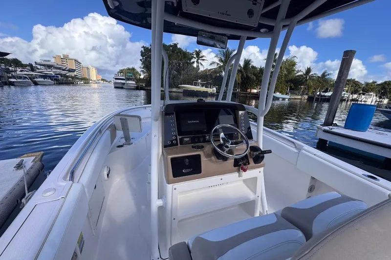 Slide: The Image of 2020 Robalo R242 Explorer boat interior with steering console, docked in a scenic marina. - 21