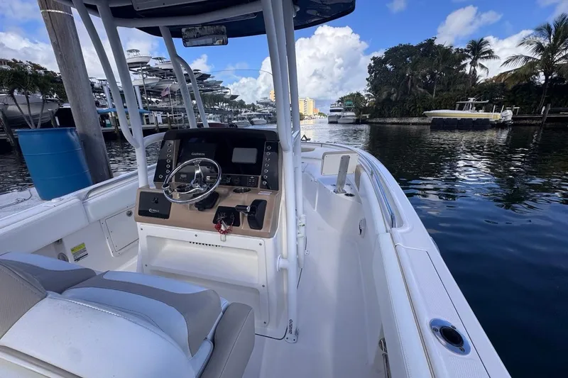 Slide: The Image of 2020 Robalo R242 Explorer boat interior with steering console, docked by a scenic waterfront. - 27