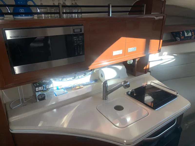 Slide: The Image of 2009 Sea Ray 270 Sundancer galley with microwave, sink, and storage cabinets. - 10