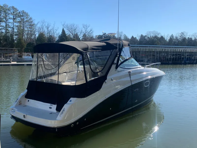 Slide: The Image of 2009 Sea Ray 270 Sundancer boat docked on calm water, with trees in the background. - 2